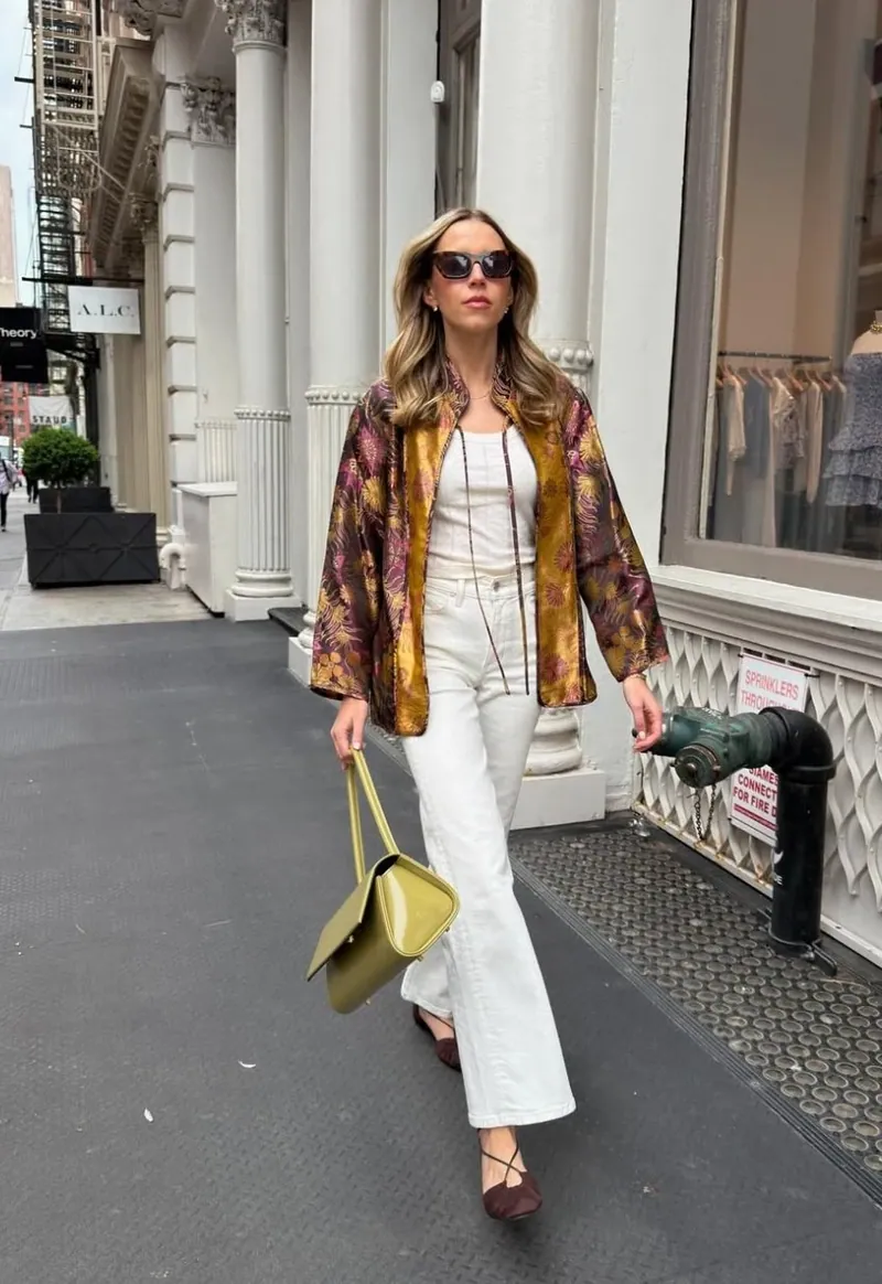 Annie in a gold brocade jacket and white jeans on a SoHo sidewalk