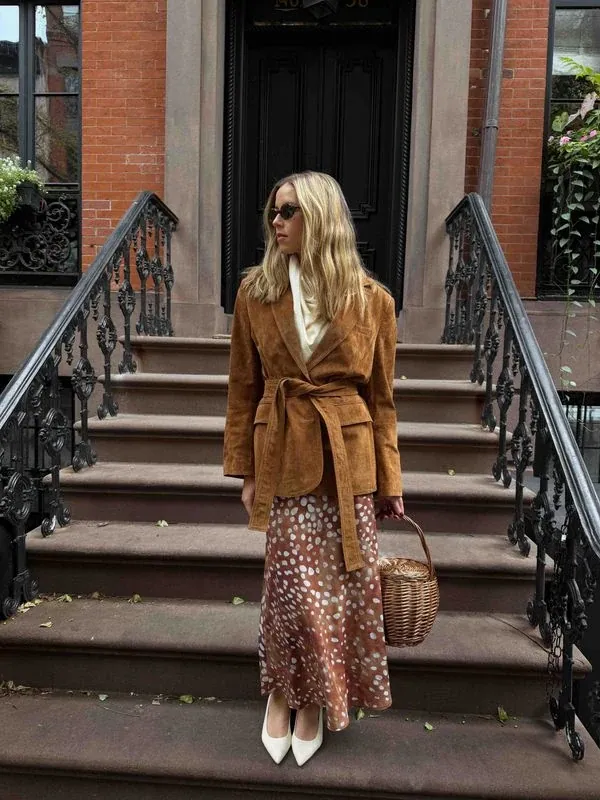 Annie on a brownstone stoop in a camel coat and leopard skirt
