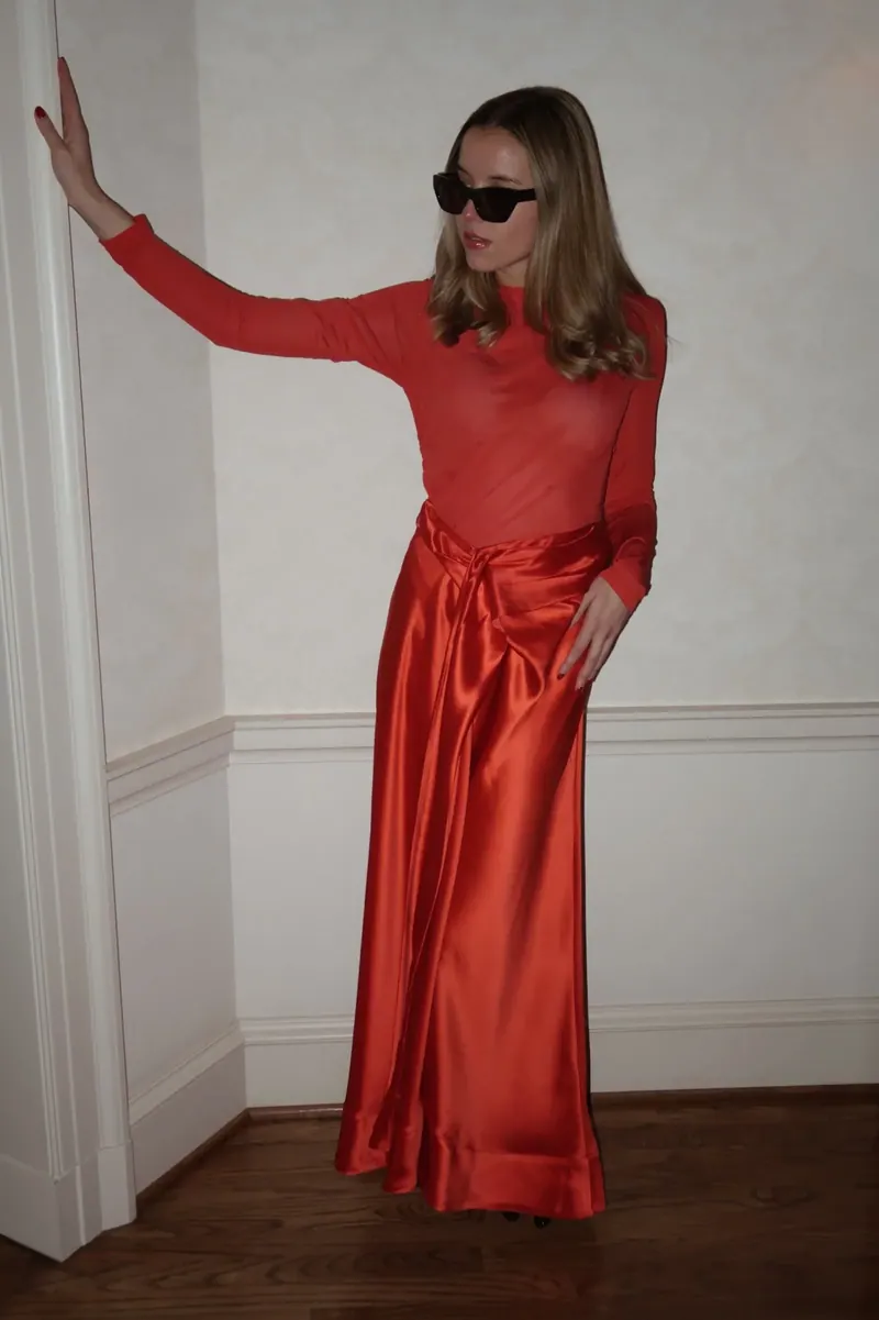 Annie in a red satin set against a white wall